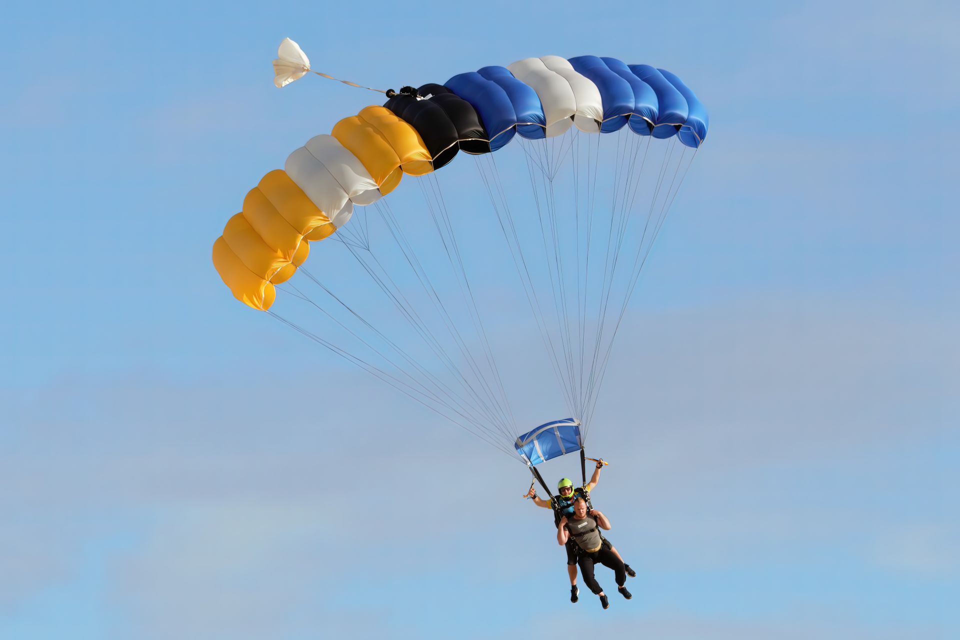 Two pilots sharing a tandem canopy at golden hour