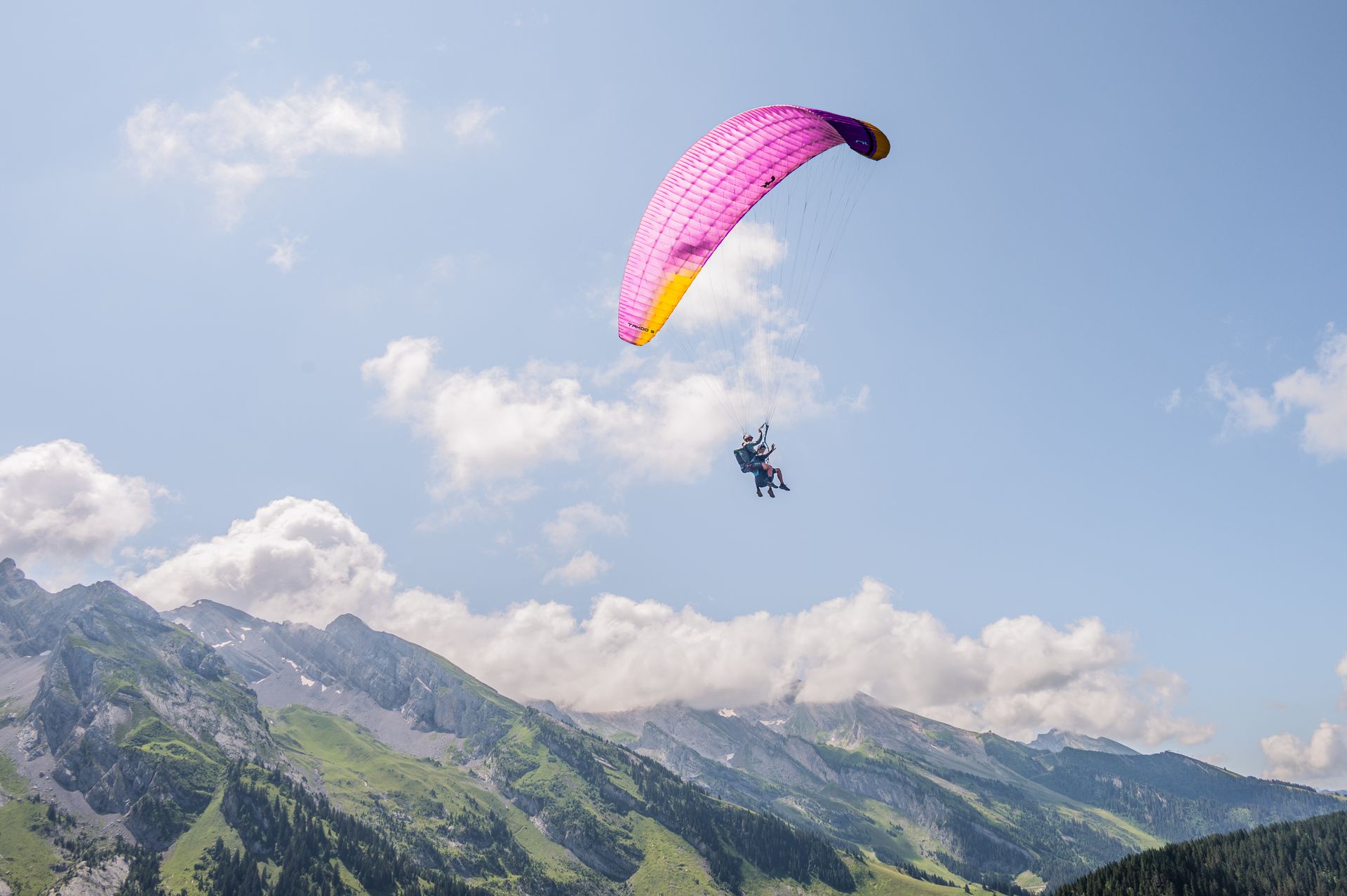 Tandem paragliding flight high above alpine peaks